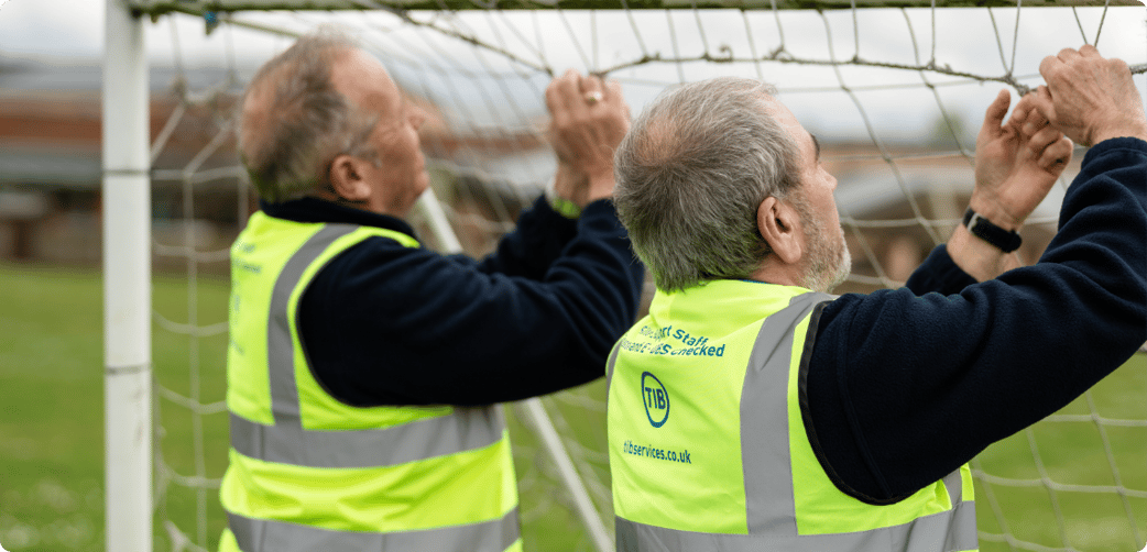 Andy and another TIB operative assemble a goal on a school playing field