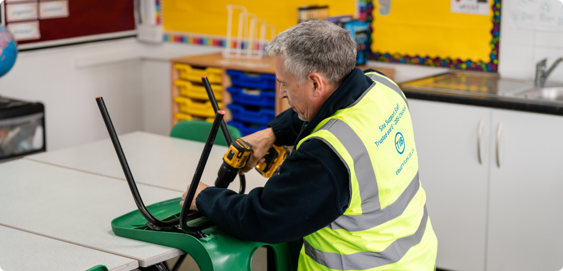 A former engineer working for TIB Services as a caretaker fixes a school chair