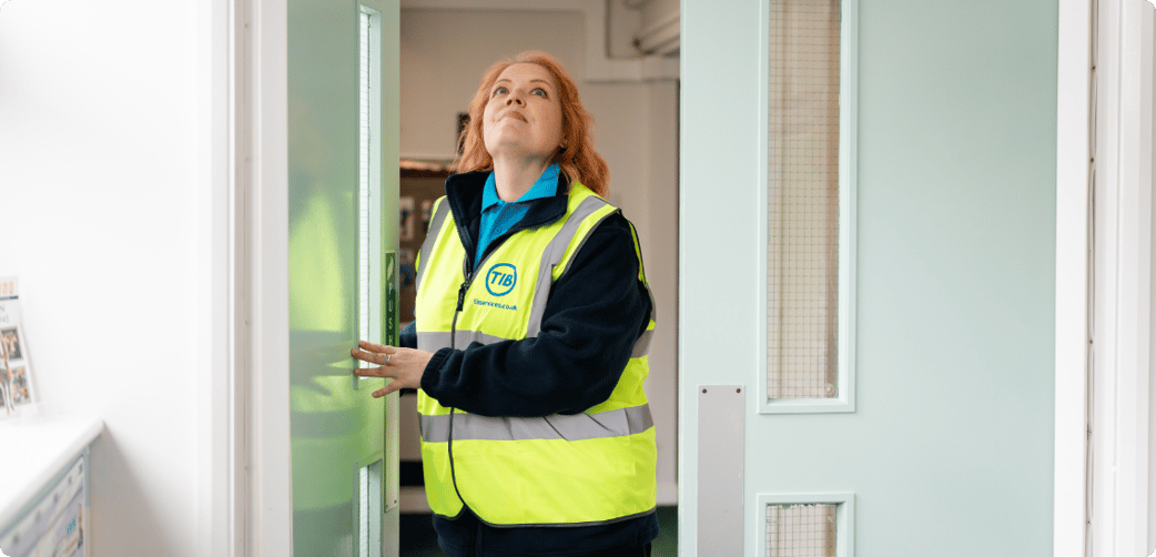 Elizabeth check a fire door at a local school while wearing a TIB high vis