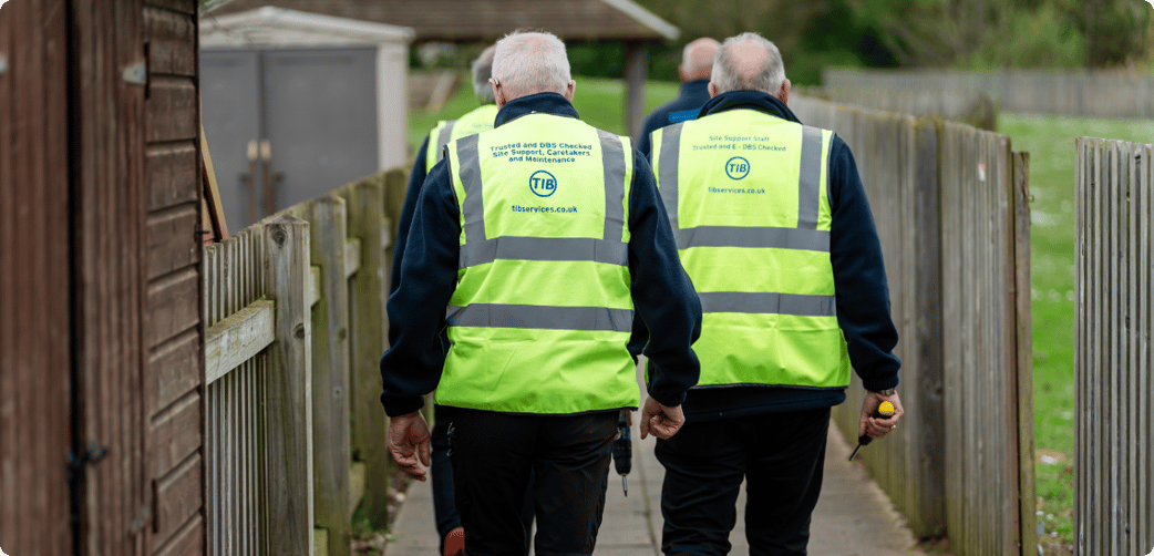 A shot behind TIB operatives walking through school grounds while wearing TIB high vis jackets