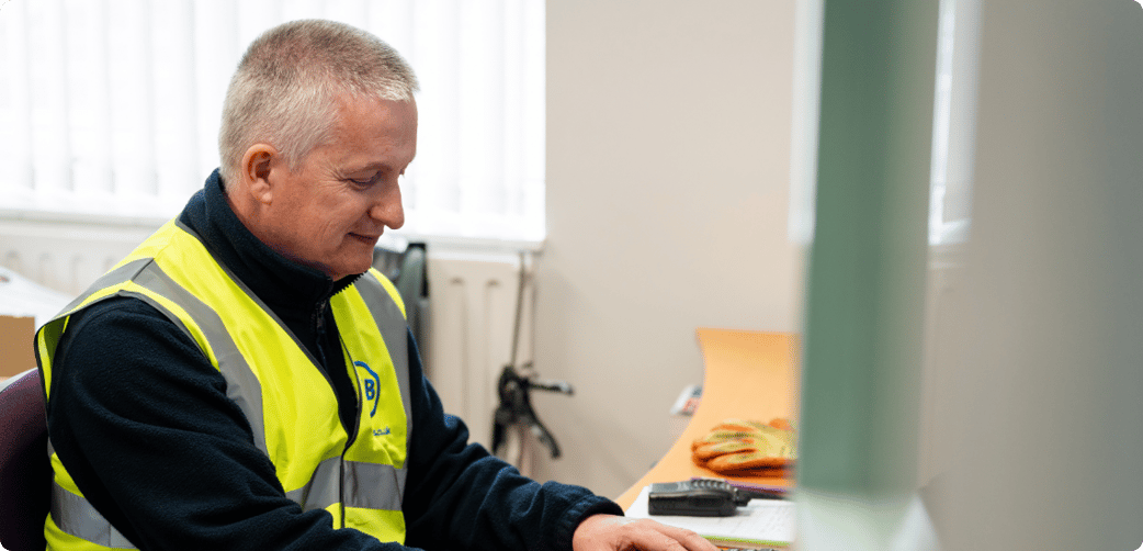 Leigh types at a school computer while wearing a TIB high vis