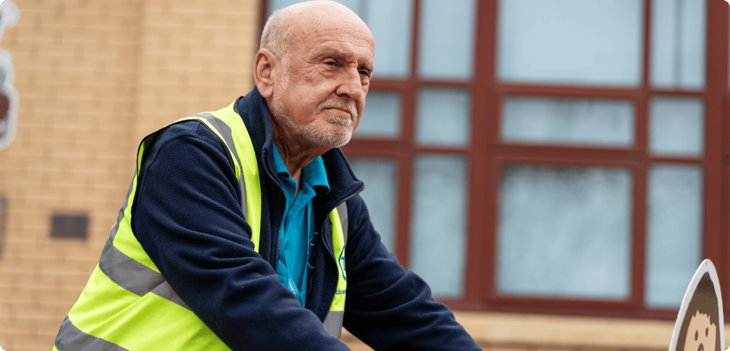 Tim pushes a sign in a school playground while wearing a TIB high vis