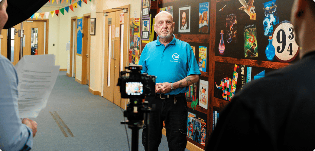 Behind-the-scenes image of Tim being filmed at a local school while wearing a TIB polo shirt