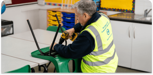 A TIB operative fixes a school chair using a drill