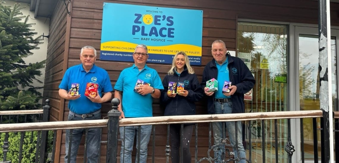 TIB volunteers pose in front of Zoe's Place Baby Hospice while holding Easter eggs