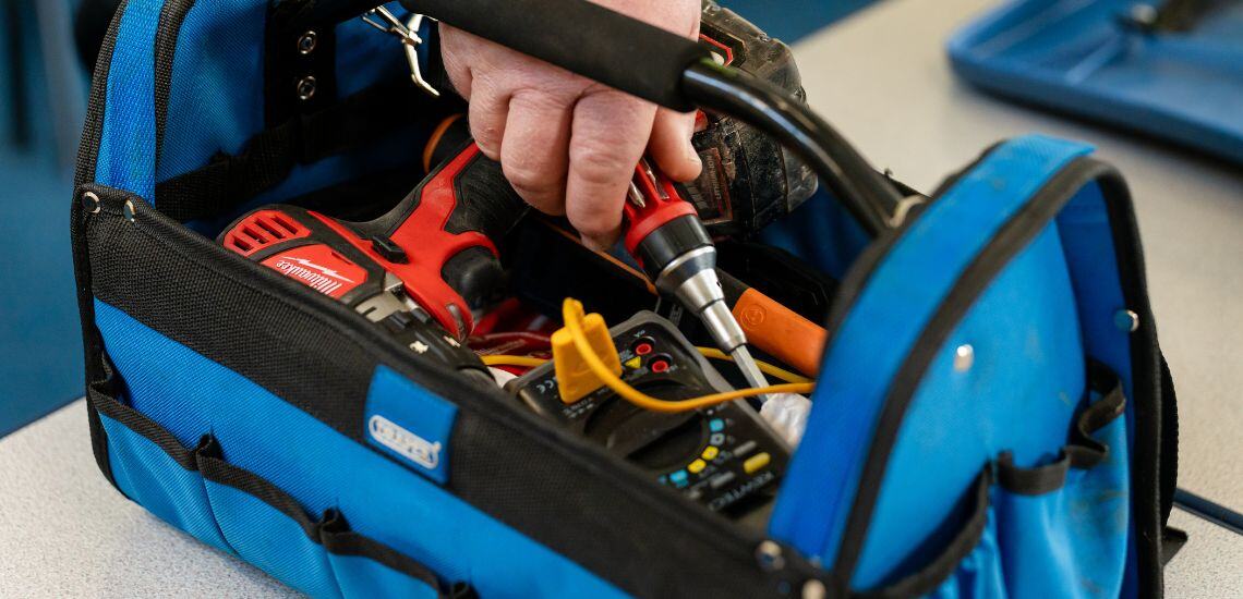 A TIB operative reaching into a toolbox to pull out a screwdriver