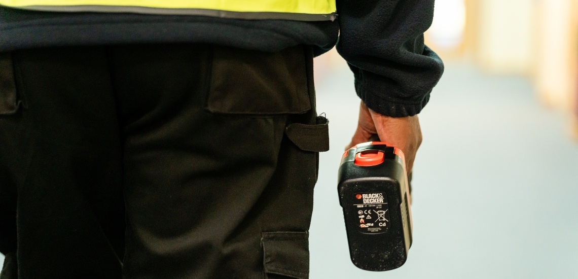 A close up of a TIB Services school caretaker holding a drill