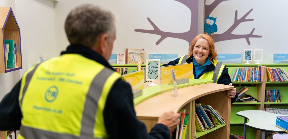 Two TIB Services caretakers move a bookcase in a school library