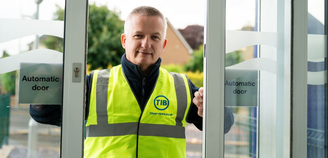 A TIB Services school caretaker smiles through automatic doors