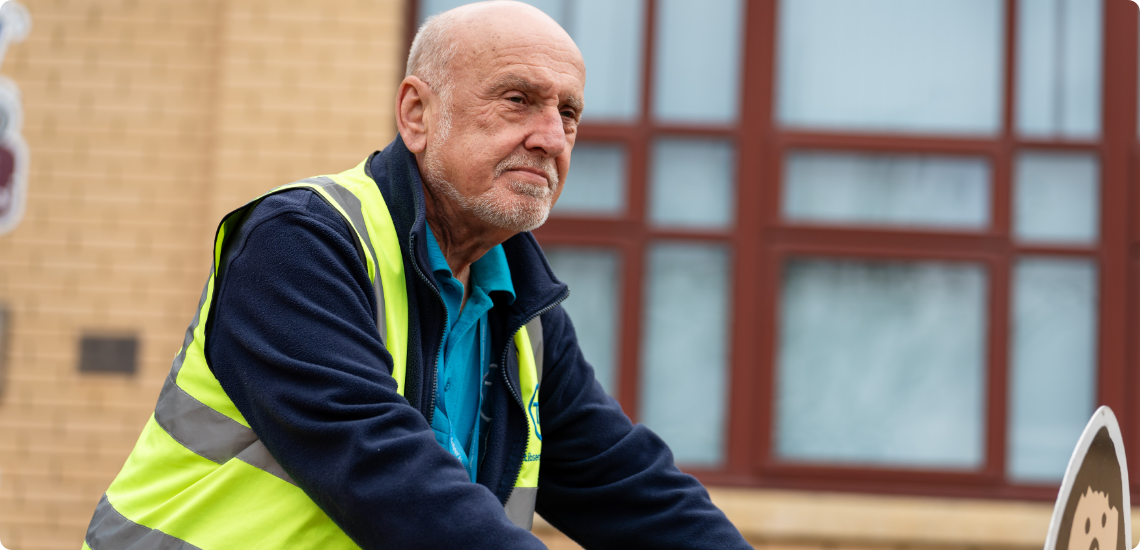 Tim in front of a school while wearing a TIB high vis