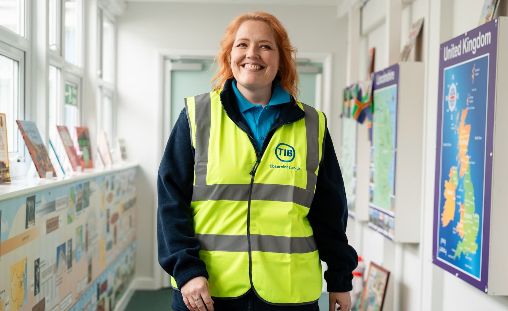 A TIB operative walks through a school corridor while wearing a high vis jacket